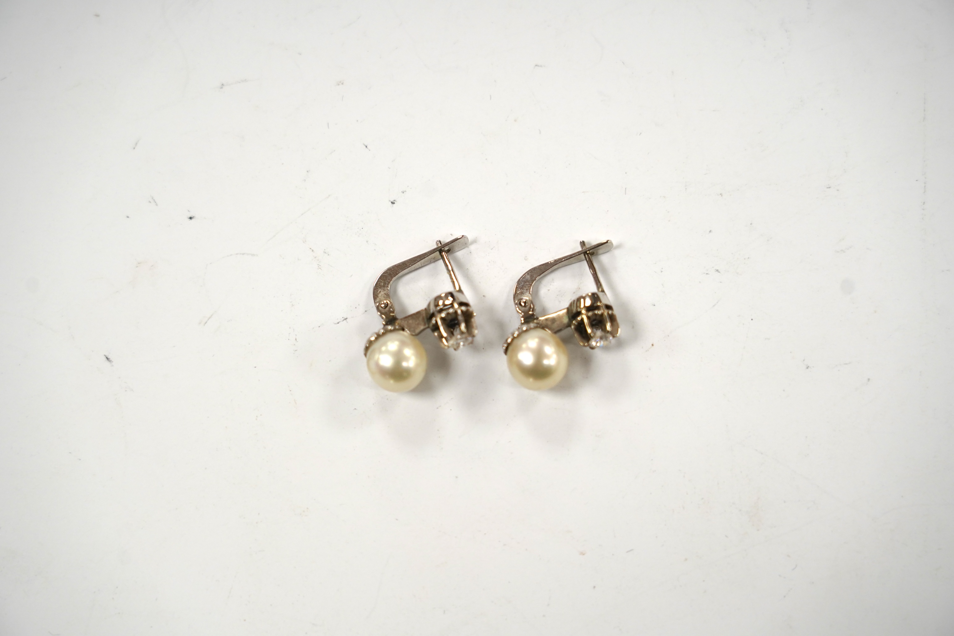 A pair of white metal, single stone cultured pearl and single stone diamond set earrings, 16mm, gross weight 4.8 grams.